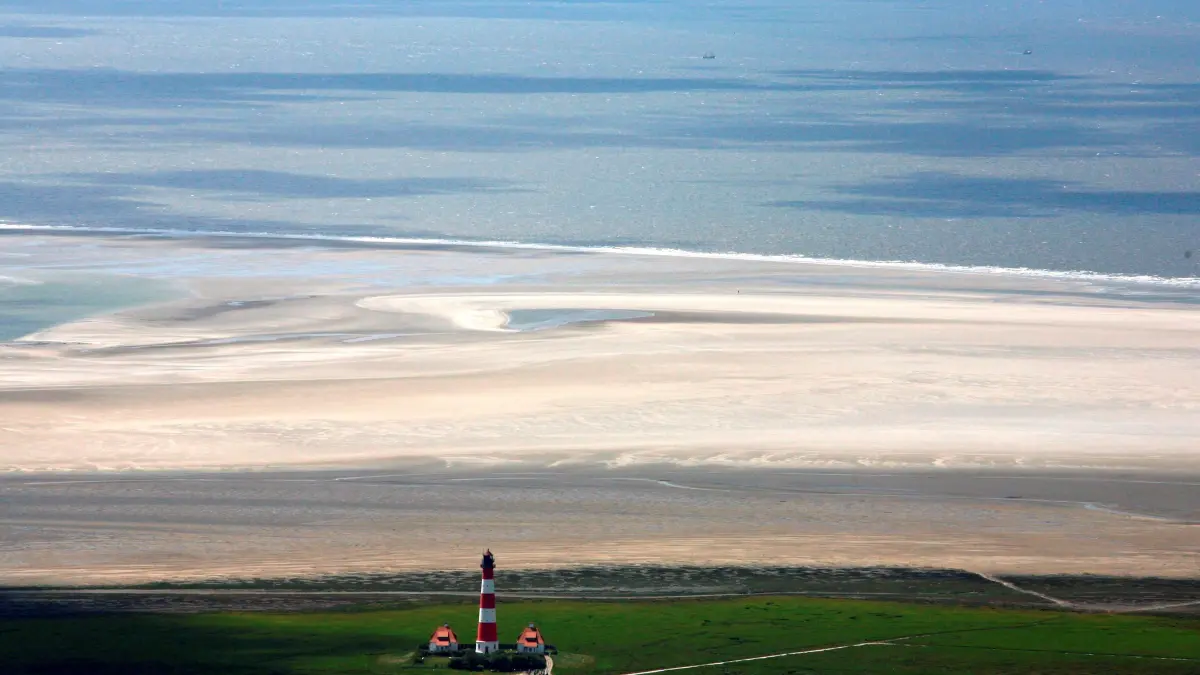 ARCHIV - Blick bei Niedrigwasser auf das Wattenmeer und den Leuchtturm von Westerhever an der schleswig-holsteinischen Nordseeküste (Foto vom 16.06.2009). Der Nationalpark Schleswig-Holsteinisches Wattenmeer feiert in diesem Jahr sein 30-jähriges Jubiläum. Am 1. Oktober 1985 wurde Deutschlands größter Nationalpark per Gesetz Realität. Foto: Carsten Rehder/dpa (zu dpa «Nationalpark Wattenmeer feiert 30-jähriges Jubiläum» vom 28.03.2015) +++ dpa-Bildfunk +++