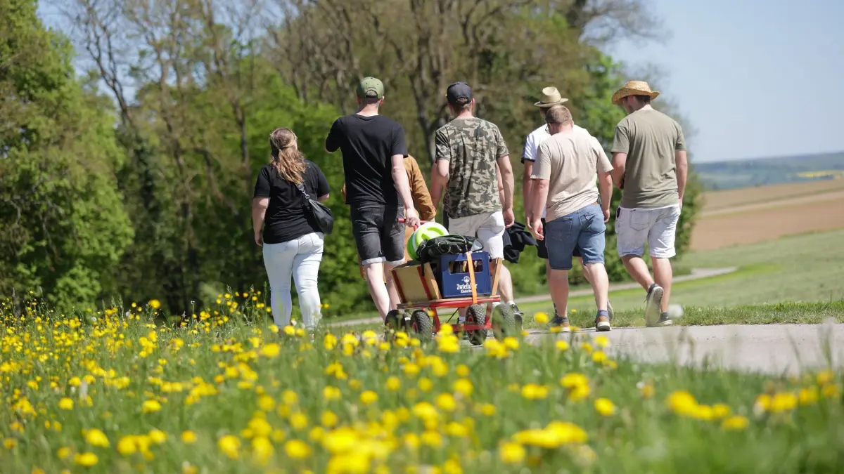 Wetter in Baden-Württemberg: 01.05.2025, Baden-Württemberg, Obermarchtal: Ausflügler wandern am 1. Mai mit einem Bollerwagen bei Reutlingendorf zu einem Maifest Foto: Thomas Warnack/dpa +++ dpa-Bildfunk +++