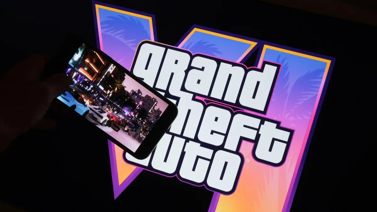 (FILES) This illustration photo created in Los Angeles, December 4, 2023, shows Rockstar Games’ Grand Theft Auto VI trailer played on a screen in front of the game title. The much-awaited release of Grand Theft Auto VI, the latest installment of the popular video game series, has been postponed by several months to May 2026, its publisher said on May 2, 2025. (Photo by Chris DELMAS / AFP)