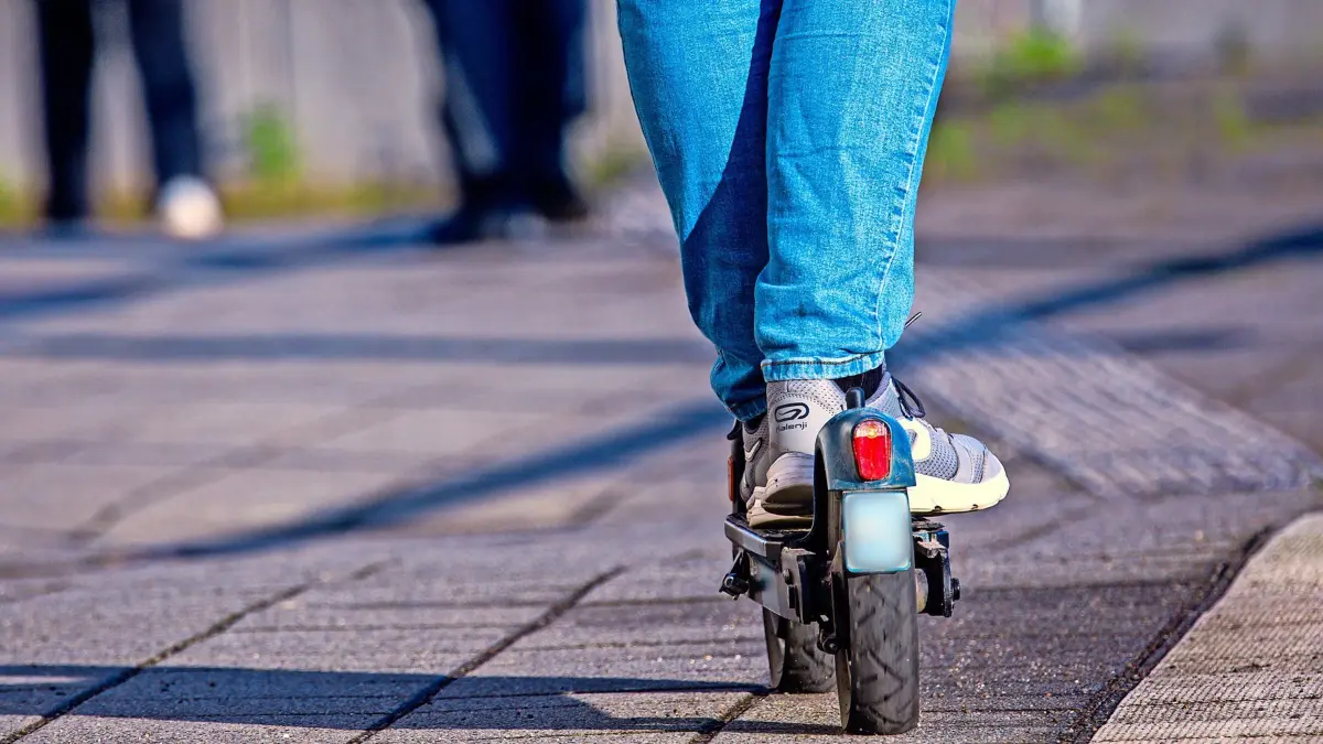 ARCHIV - 17.04.2024, Mecklenburg-Vorpommern, Wismar: Ein Reisender fährt mit seinem E-Scooter über den Bahnsteig. (zu dpa: «E-Roller werden in Frankfurter U- und Straßenbahnen verboten») Foto: Jens Büttner/dpa +++ dpa-Bildfunk +++