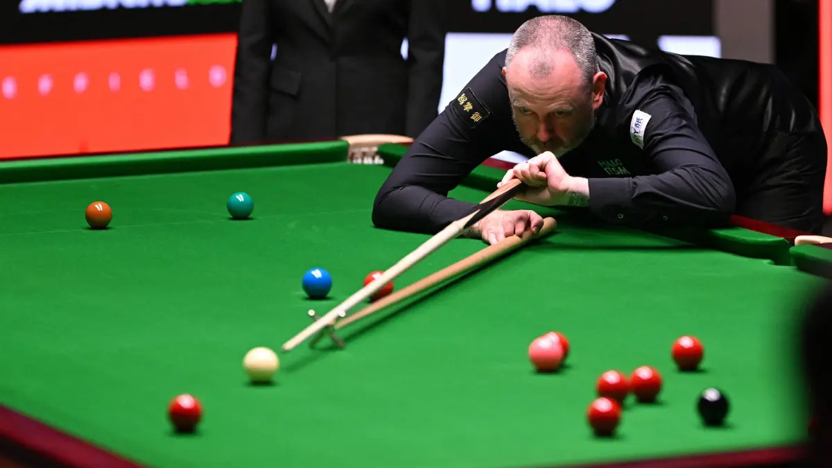 Wales' Mark Williams plays a shot with the rest on day two of his World Championship Snooker final against China's Zhao Xintong during the final session at The Crucible in Sheffield, northern England on May 5, 2025. (Photo by Oli SCARFF / AFP)