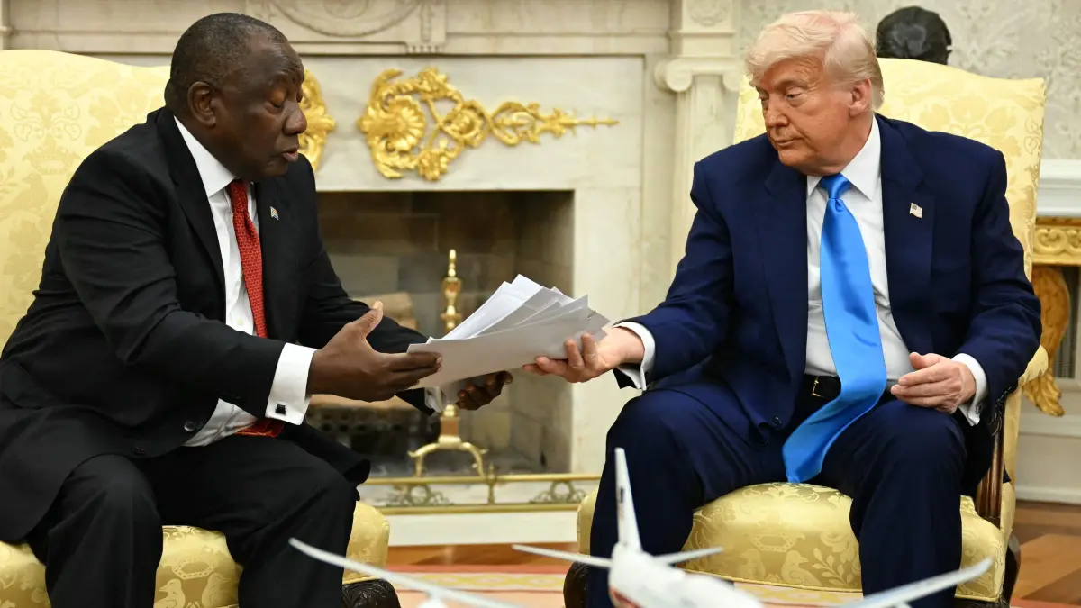 US President Donald Trump hands papers to South African President Cyril Ramaphosa during a meeting in the Oval Office of the White House in Washington, DC, on May 21, 2025. South African President Cyril Ramaphosa meets Donald Trump on Wednesday amid tensions over Washington's resettlement of white Afrikaners that the US president claims are the victims of "genocide." (Photo by Jim WATSON / AFP)