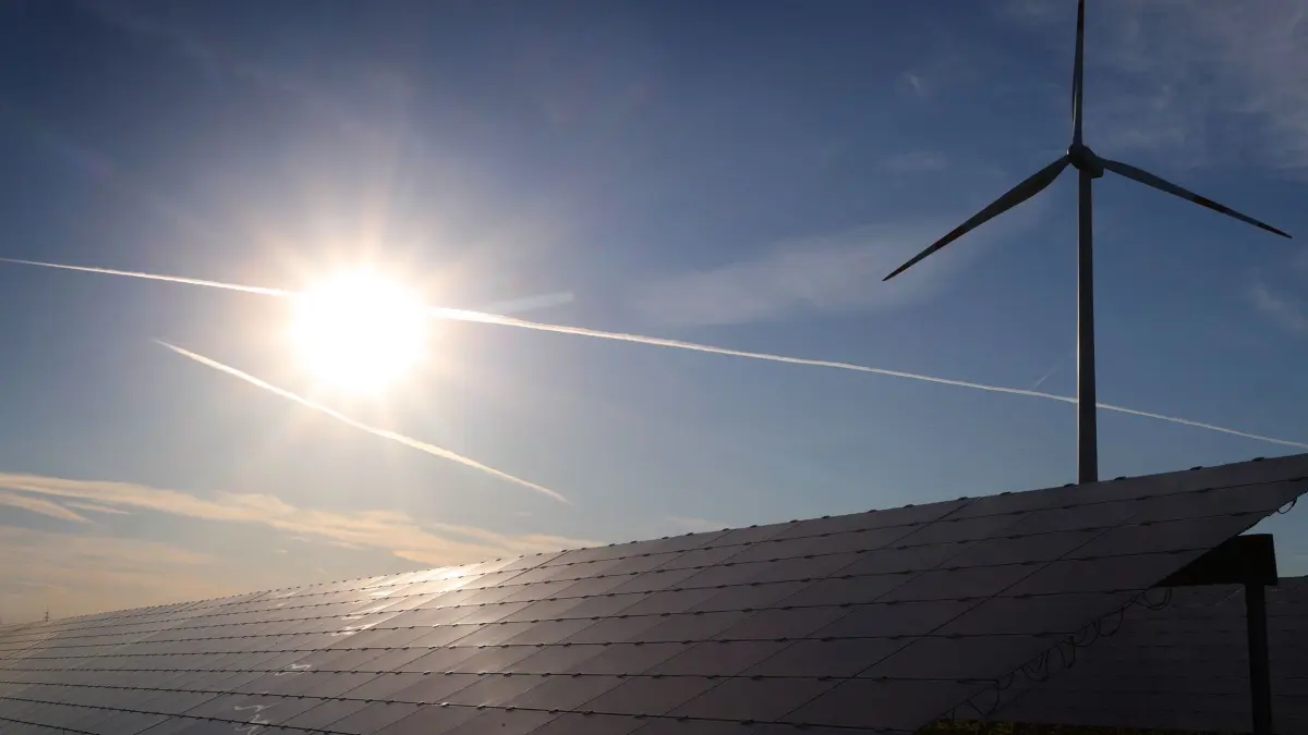 Windrad hinter Solarkraftanlage: ARCHIV - 02.06.2021, Bayern, Kitzingen: Ein Windrad steht hinter den Solarzellen einer Solarkraftanlage im Sonnenschein. (zu dpa: «Grüne: Staatsregierung erwägt Wortbruch in Energiepolitik») Foto: Karl-Josef Hildenbrand/dpa +++ dpa-Bildfunk +++