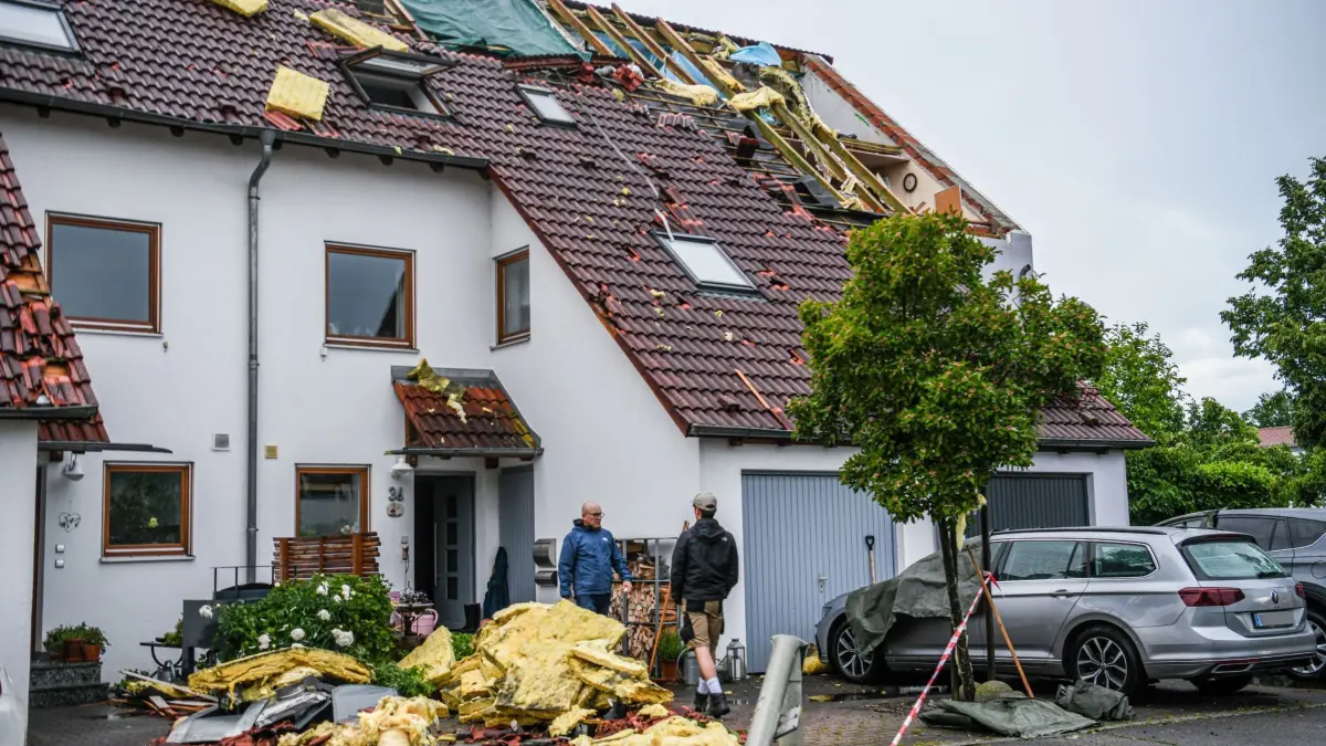 Nach dem Unwetter in Baden-Württemberg - Donaustetten: 04.06.2025, Baden-Württemberg, Ulm: Nach dem Unwetter ist das Dach eines Reihenhauses im Stadtteil Donaustetten stark beschädigt. Menschen seien nicht verletzt worden. Die Feuerwehr gehe von einer starken Windhose aus. In einem Radius von einem Kilometer gebe es sehr starke Beschädigungen - teilweise seien es nur einzelne abgedeckte Dachplatten, teilweise ganze Dächer. Foto: Jason Tschepljakow/dpa - ACHTUNG: Kennzeichen wurden aus rechtlichen Gründen gepixelt +++ dpa-Bildfunk +++