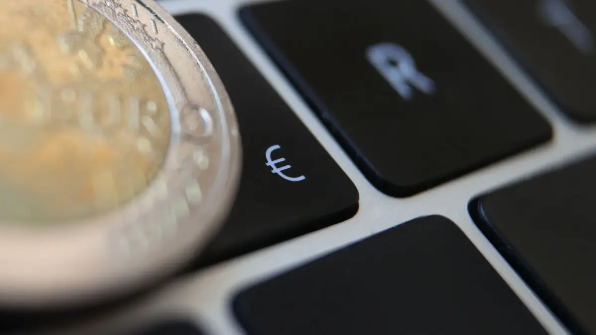 Symbolbild - Digitaler Euro: ARCHIV - 01.06.2021, Bayern, Augsburg: Eine Zwei-Euro-Münze liegt auf der Tastatur eines Laptops neben einem Eurozeichen. Die Einführung des digitalen Euros wird nach einer Studie der Beratungsgesellschaft PwC erhebliche Kosten für europäische Banken verursachen. (zu dpa: «Studie: Hohe Kosten für Einführung des digitalen Euro») Foto: Karl-Josef Hildenbrand/dpa +++ dpa-Bildfunk +++