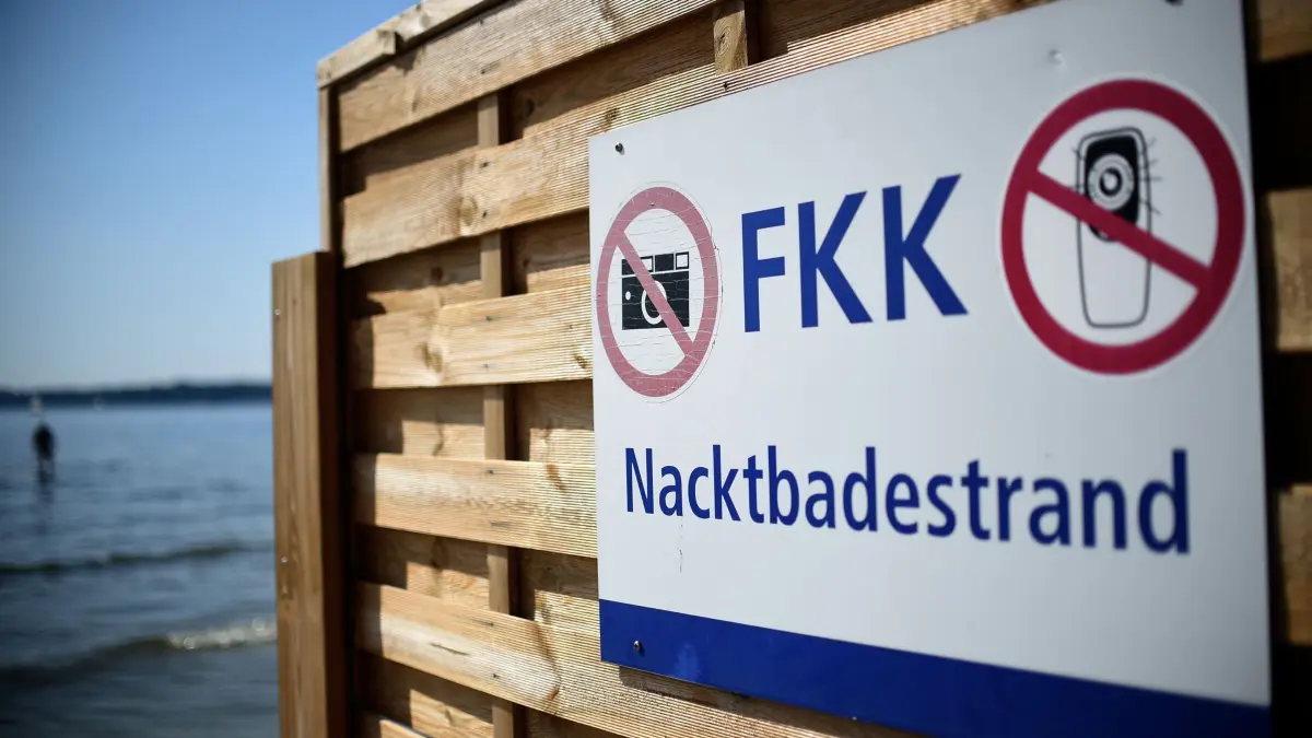 FKK-Strand: ARCHIV - 16.07.2015, Berlin: Das FKK-Schild im Standbad Wannsee in Berlin weist auf den Nacktbadestrand hinter dem Sichtschutz hin. Am Bodensee ist ein neuer FKK-Strand geplant. Doch wie verhält man sich als Nacktbader eigentlich korrekt? (zu dpa: «Nackt an den See – was ist erlaubt, was nicht?») Foto: Britta Pedersen/dpa +++ dpa-Bildfunk +++