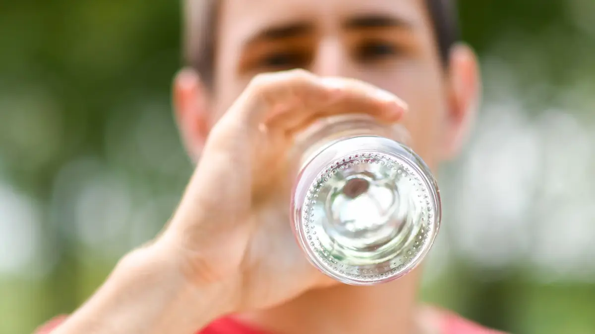 Mann trinkt aus einer Wasserflasche: ILLUSTRATION - Wie viel habe ich heute schon getrunken? Eine Stressexpertin rät zum regelmäßigen Innehalten, um den Stress-Autopilot zu durchbrechen. (zu dpa: «Gesund essen trotz Stress? 4 Strategien, wie es klappen kann») Foto: Tobias Hase/dpa-tmn - Honorarfrei nur für Bezieher des dpa-Themendienstes +++ dpa-Themendienst +++
