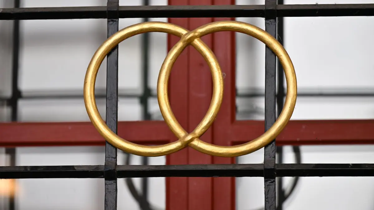 Eheringe: ARCHIV - 17.06.2022, Thüringen, Erfurt: Zwei goldene Ringe am Fenstergitter eines Hochzeitshauses aus dem 16. Jahrhundert. (zu dpa: «Neues Recht für Familiennamen beschäftigt Standesämter») Foto: Martin Schutt/dpa +++ dpa-Bildfunk +++