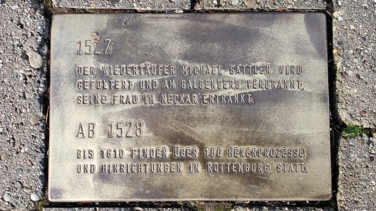 Diese Gedenkplatte im Rottenburger Geschichtspfad erinnert an den in der Reformationszeit getöteten Täufer Michael Sattler sowie Hexenprozesse in Rottenburg und zeugt damit von Gewalt, die im Namen der christlichen Religion verübt wurde.