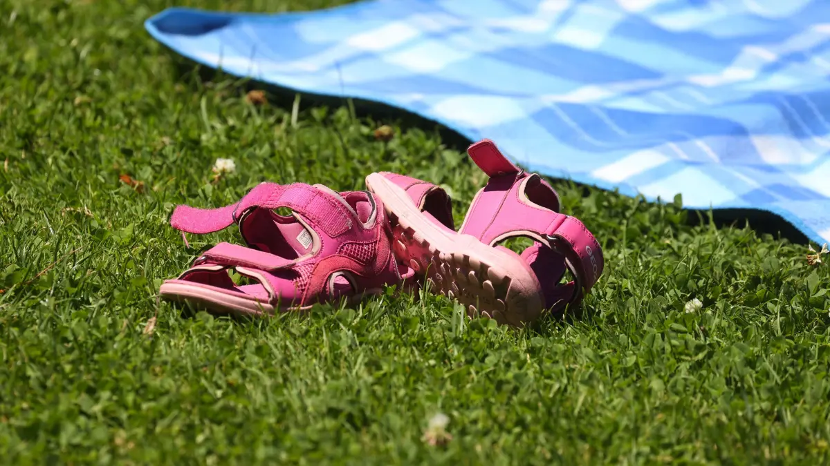 Kinderschuhe liegen am Ufer des Strandbades neben einer Decke. Anspruch auf Hitzefrei hat kein Kind. Die heutigen Regelungen dazu sind von Bundesland zu Bundesland unterschiedlich. (zu dpa "Früher gab's Hitzefrei - heute meist Aufsichtspflicht statt Badesee") +++ dpa-Bildfunk +++