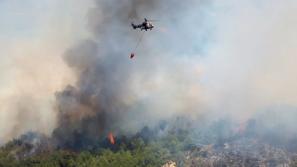 Brände in der Türkei: 30.06.2025, Türkei, Seferihisar: Ein Hubschrauber lässt Wasser ab, um ein Feuer in der Nähe von Izmir zu löschen. Einsatzkräfte in der Türkei kämpfen in mehreren Provinzen gegen Brände, die sich bei starken Winden ausbreiten. Foto: Cengiz Malgir/DIA Photo via AP/dpa +++ dpa-Bildfunk +++