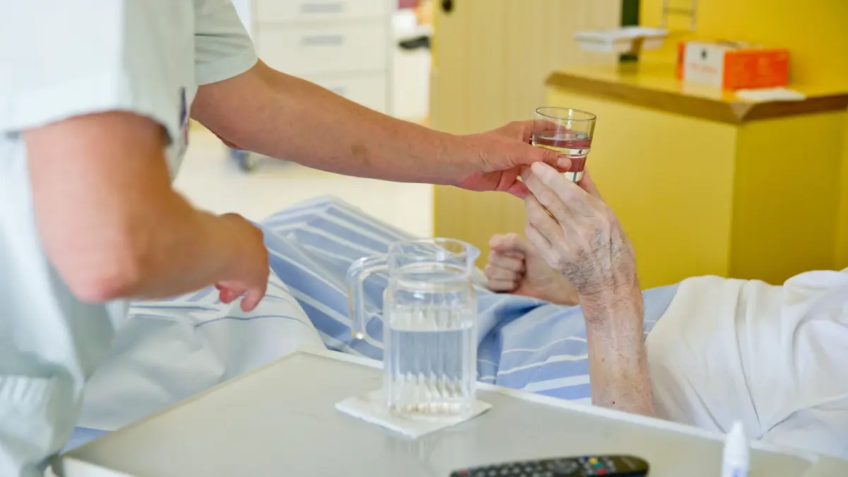 Hitzewelle: Kliniken und Pflegeheime in Sachsen sind vorbereitet: ARCHIV - 01.07.2015, Bayern, Nürnberg: Eine Krankenpflegerin reicht einem Patienten ein Glas Wasser. (Zu dpa «Hitzewelle: Kliniken und Pflegeheime in Sachsen sind vorbereitet» ) (zu dpa: «Statistiker: Hitze fordert jährlich rund 22 Tote») Foto: Daniel Karmann/dpa +++ dpa-Bildfunk +++
