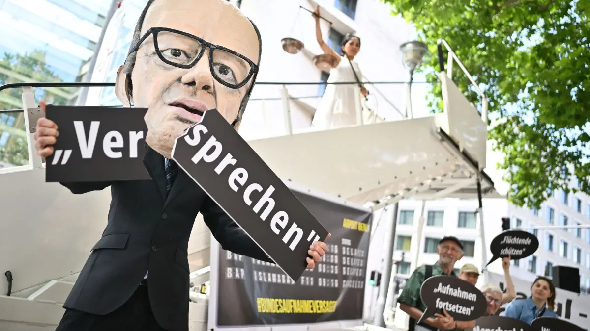 Protestaktion von Organisation „Kabul Luftbrücke“: ARCHIV - 20.06.2025, Berlin: Ein Aktivist mit Merz-Maske zerbricht während einer symbolischen Protestaktion von Kabul Luftbrücke und Campact zur Unterstützung von Klagen von Afghanen gegen die Bundesregierung vor dem Auswärtigen Amt ein Schild mit der Aufschrift „Versprechen“. Im Hintergrund steht eine als Justitia verkleidete Aktivistin. Bei den Klagen am Verwaltungsgericht Berlin geht es um Eilanträgen auf Erteilung von Visa für gefährdeten Afghanen mit Aufnahmezusage in Pakistan. (zu dpa: «Gericht: Bundesregierung muss Afghanen Visa erteilen») Foto: Sebastian Gollnow/dpa +++ dpa-Bildfunk +++