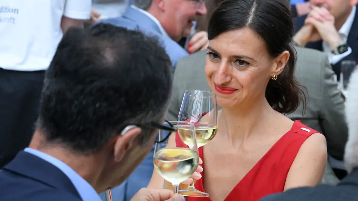 „Stallwächterparty“ Landesvertretung Baden-Württemberg: 10.07.2025, Berlin: Cem Özdemir (Bündnis 90/Die Grünen), Spitzenkandidat von Bündnis 90/Die Grünen für die Landtagswahl in Baden-Württemberg. und seine Partnerin Flavia Zaka stoßen während der 60. "Stallwächterparty" in der Landesvertretung Baden-Württemberg mit einem Glas Wein an. Foto: Jens Kalaene/dpa +++ dpa-Bildfunk +++