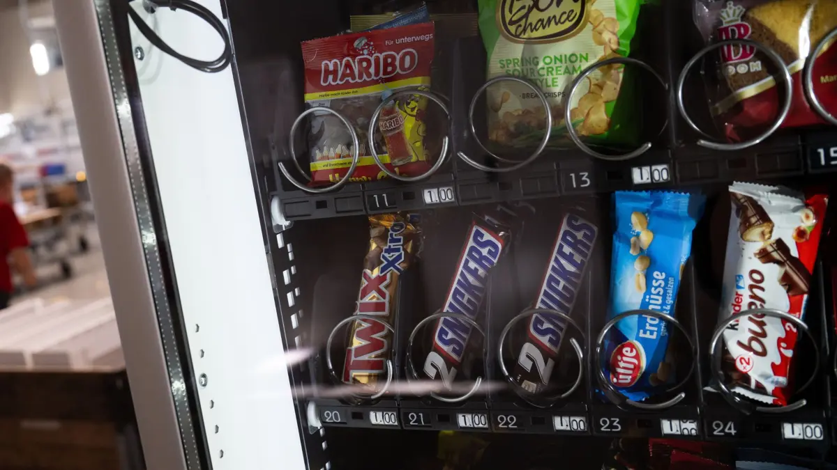 Ein Automat mit Süßigkeiten und Snacks steht in einer Fabrikhalle.