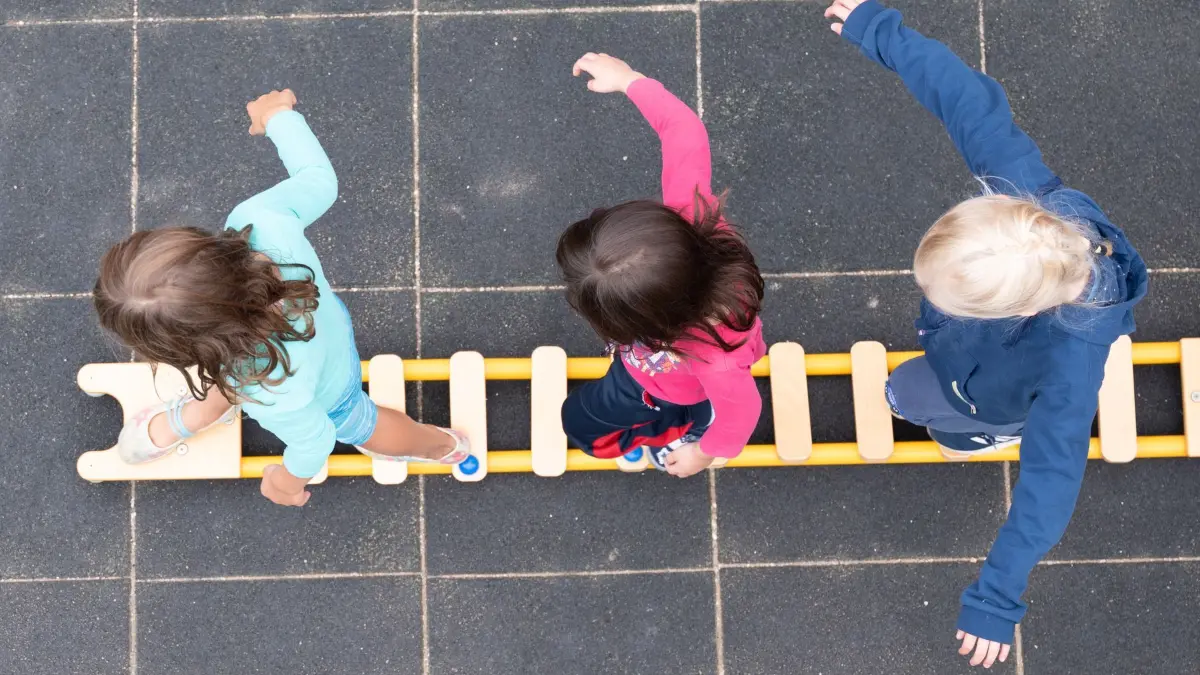 Kindertagesstätte: ARCHIV - 20.08.2021, Sachsen, Dresden: Kinder balancieren während eines Pressetermins auf dem Spielplatz einer Kita auf einem Brett. (zu dpa: «Kita-Standards - empörter Aufschrei von Elternvertretern») Foto: Sebastian Kahnert/dpa-Zentralbild/dpa +++ dpa-Bildfunk +++