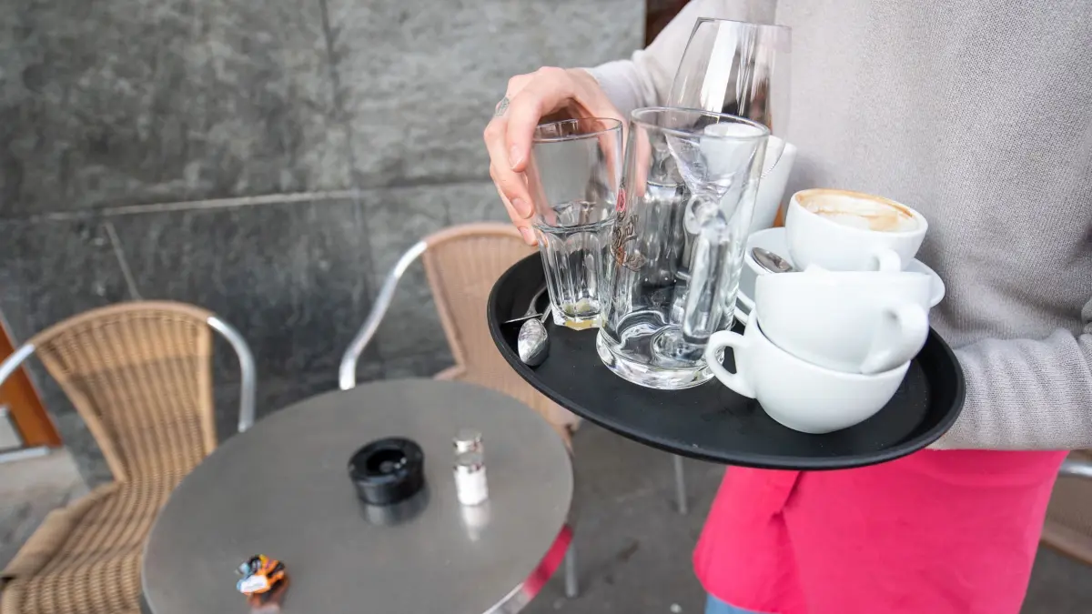 Ferienjobs für Schüler und Studierende: ARCHIV - 17.03.2020, Baden-Württemberg, Stuttgart: Ein Kellner räumt einen Tisch in einem Restaurant ab. (zu dpa: «Ferienjobs in Hessen - mehr als nur Geld verdienen») Foto: Sebastian Gollnow/dpa +++ dpa-Bildfunk +++