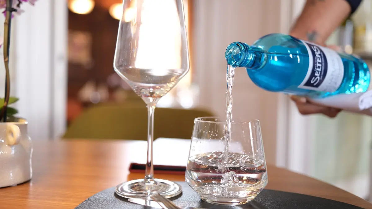 Gastronomie: ARCHIV - 27.02.2025, Baden-Württemberg, Stuttgart: In einem Restaurant schenkt ein Kellner einem Gast ein Glas Mineralwasser ein (gestellte Szene). (zu dpa: «Drohen steigende Preise? Tarifrunde bei Hotels und Gastro») Foto: Bernd Weißbrod/dpa +++ dpa-Bildfunk +++