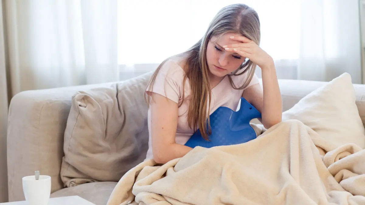Eine Frau krank auf dem Sofa: ILLUSTRATION - Kopfschmerzen, Gliederschmerzen und natürlich übler Brechreiz: Das sind nur drei Anzeichen für eine Infektion mit dem Noro-Virus. (zu dpa: «Fieser Magen-Darm-Infekt: 7 Fragen zum Norovirus») Foto: Christin Klose/dpa-tmn - Honorarfrei nur für Bezieher des dpa-Themendienstes +++ dpa-Themendienst +++