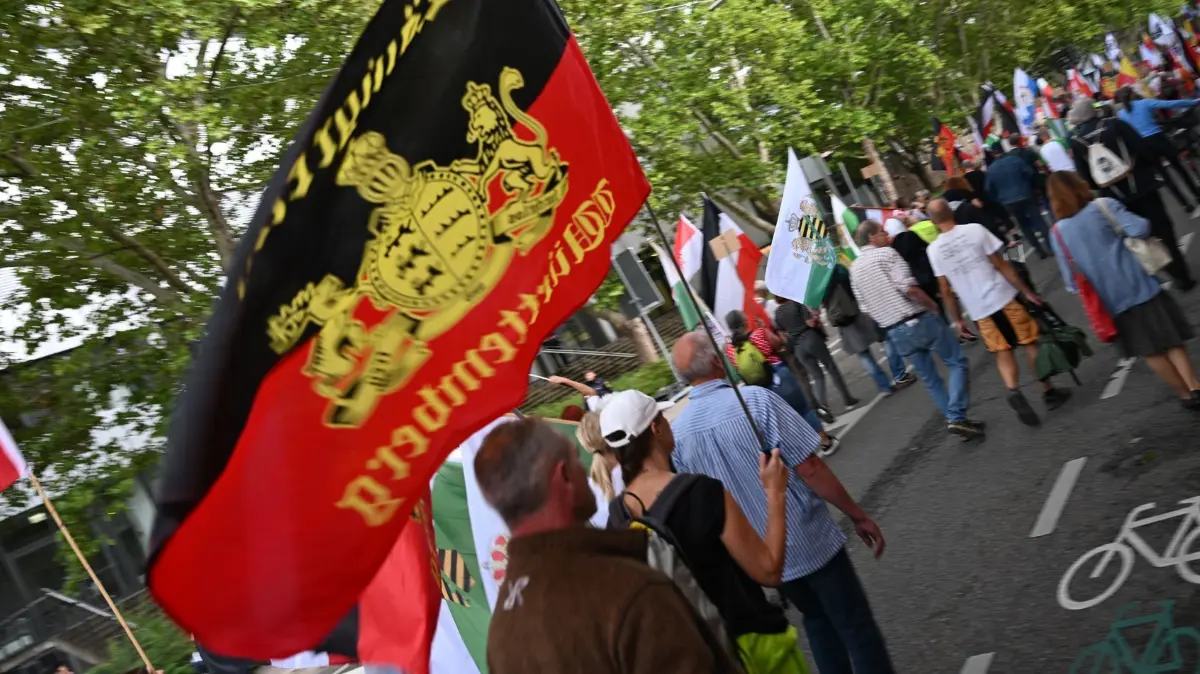 „Reichsbürger“-Treffen in Karlsruhe: 26.07.2025, Baden-Württemberg, Karlsruhe: Teilnehmer einer Kundgebung von «Reichsbürgern» ziehen mit Fahnen durch die Innenstadt. Das Treffen der «Reichsbürger» war angemeldet unter dem Motto «Das sechste große Treffen der Bundesstaaten, Heimath und Weltfrieden». Foto: Frm/dpa +++ dpa-Bildfunk +++
