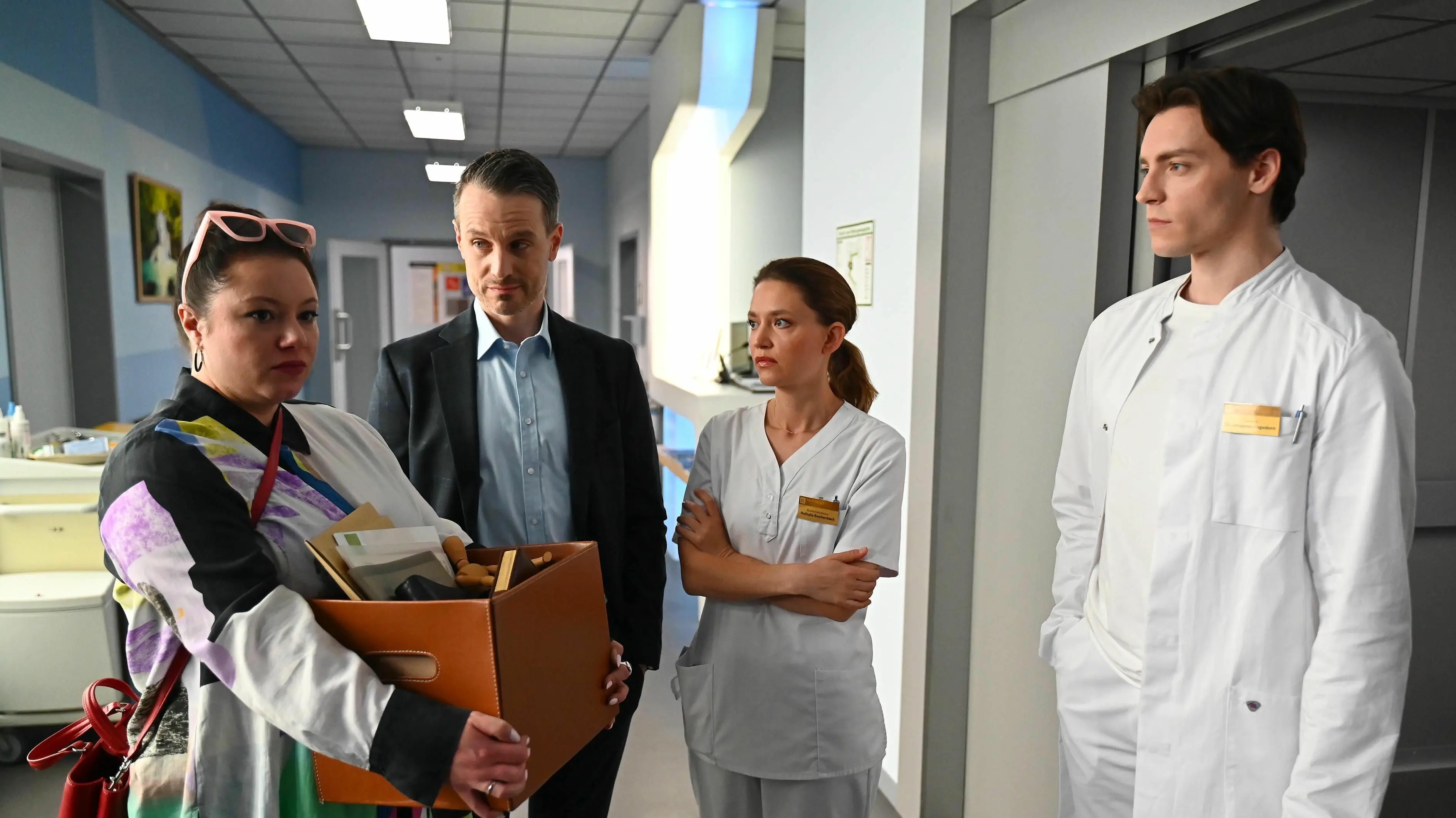 Kilian (Marc Dumitru, 2.v.r.) triumphiert über Vanessa (Julia Augustin, l.). Johannes (Maximilian Schneider) ahnt hier noch nicht, dass er die Klinik bald auch verlassen muss.
