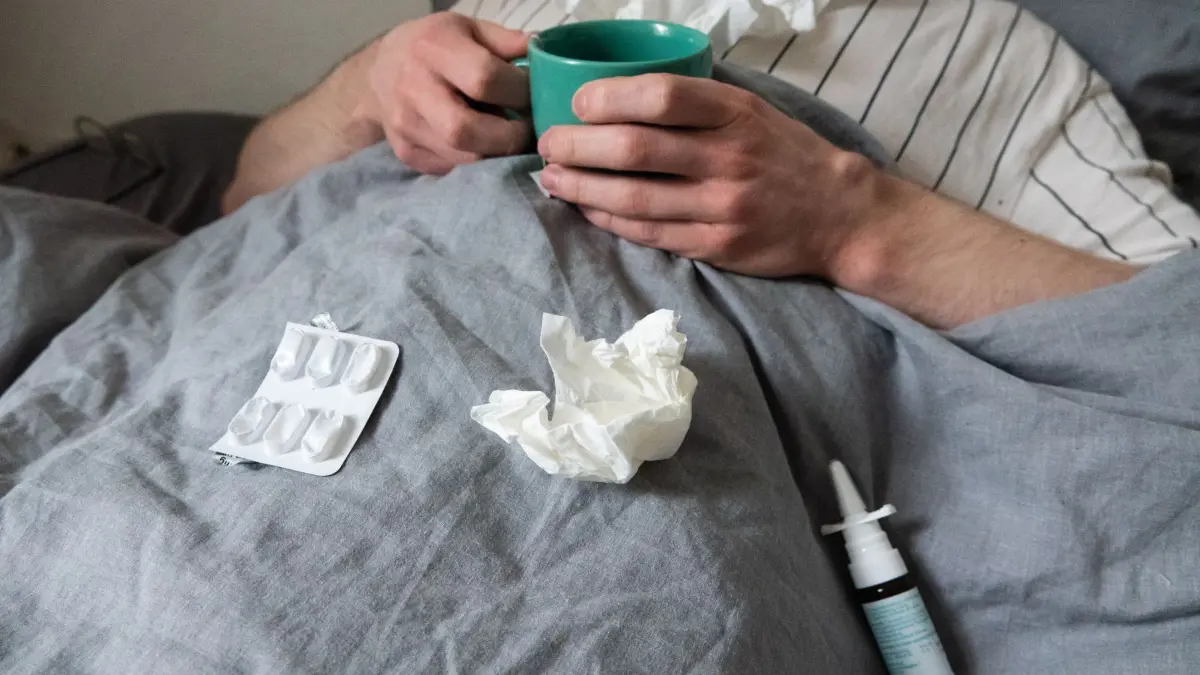 Atemwegserkrankungen in Deutschland: ARCHIV - 12.12.2023, Niedersachsen, Hannover: Ein Mann liegt mit Taschentüchern, Teetasse, Nasenspray und Tabletten im Bett (gestellte Szene). (zu dpa: «Erkältungswelle sorgt für hohen Krankenstand») Foto: Philip Dulian/dpa +++ dpa-Bildfunk +++