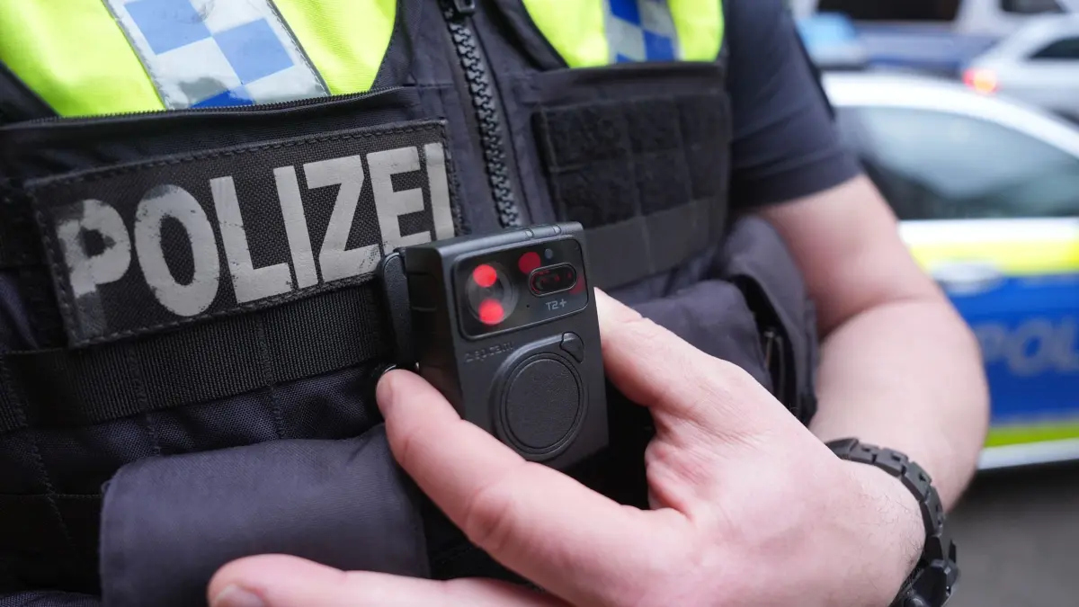 Bodycams: ARCHIV - 15.03.2024, Hamburg: ILLUSTRATION - Ein Polizist - hier in Hamburg - greift an eine Bodycam an seiner Weste. (zu dpa: «Gewalt vorbeugen - Bodycams bei Polizei und DB-Sicherheit») Foto: Marcus Brandt/dpa +++ dpa-Bildfunk +++