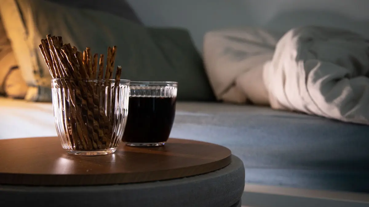 Aufgeschlagenes Bett mit Salzstangen und Cola: ILLUSTRATION - Der Elektrolytverlust bei Durchfall kann zum Beispiel mit Salzgebäck ausgeglichen werden. (zu dpa: «Noroviren, Ehec und Co.: Wann wird Durchfall gefährlich?») Foto: Christin Klose/dpa-tmn - Honorarfrei nur für Bezieher des dpa-Themendienstes +++ dpa-Themendienst +++