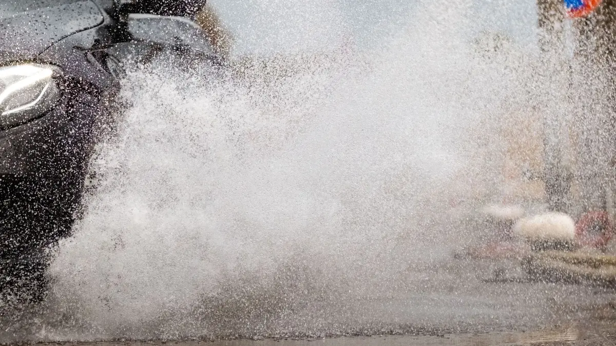 Regen auf der Fahrbahn: ARCHIV - 09.08.2018, Niedersachsen, Norddeich: 09.08.2018, Niedersachsen, Norddeich: Ein Auto fährt bei Regen durch eine große Pfütze. (zu dpa: «Drei Leichtverletzte nach Aquaplaning-Unfällen auf A73») Foto: Mohssen Assanimoghaddam/dpa +++ dpa-Bildfunk +++
