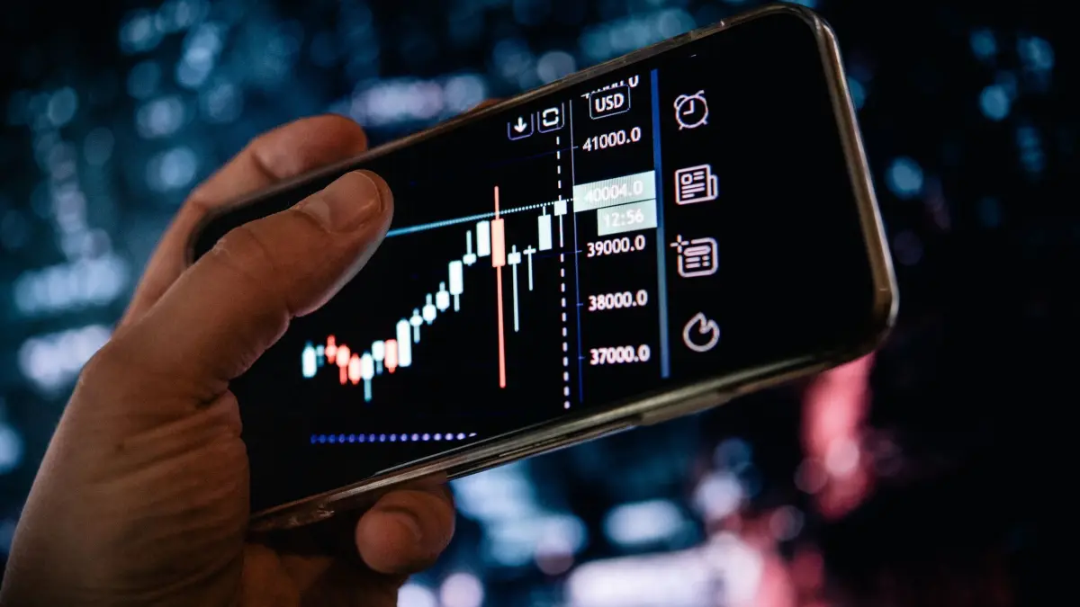 Mann schaut sich AKtienkurse auf dem Smartphone an: ILLUSTRATION - Viele Menschen kaufen Aktien, ohne sich wirklich Gedanken über ihre Anlageziele zu machen. (zu dpa: «Kopfsache Börse: Was erfolgreiche Anleger auszeichnet») Foto: Zacharie Scheurer/dpa-tmn - Honorarfrei nur für Bezieher des dpa-Themendienstes +++ dpa-Themendienst +++