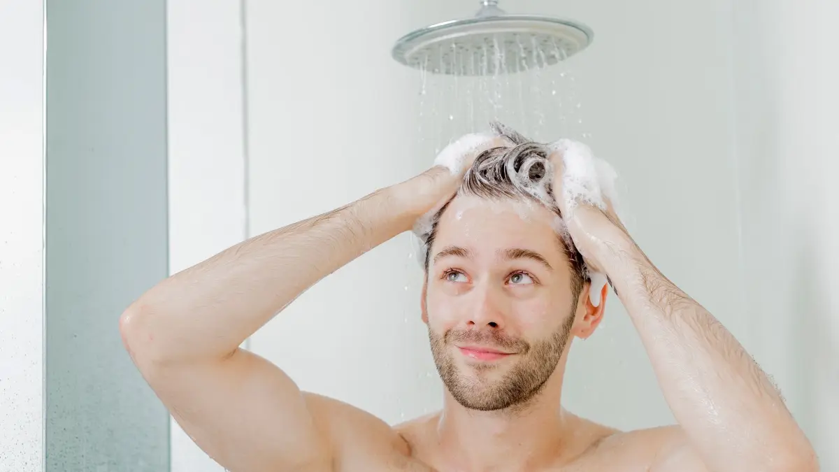 Mann wäscht sich unter der Dusche die Haare: ILLUSTRATION - Wärmetauscher in der Dusche nutzen warmes Abwasser, um Energie zu sparen. (zu dpa: «Energiesparen beim Duschen: Warmes Wasser sinnvoll nutzen») Foto: Monique Wüstenhagen/dpa-mag - Honorarfrei nur für Bezieher des Dienstes dpa-Magazin +++ dpa-Magazin +++