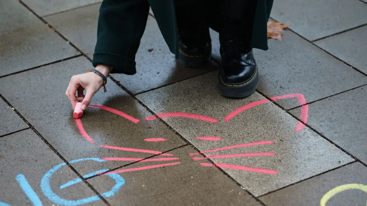 ARCHIV - 01.02.2021, Rheinland-Pfalz, Mainz: Eine Aktivistin malt mit Kreide ein Katzensymbol neben einen anzüglichen Kommentar aufs Straßenpflaster (Symbolbild). Die SPD-Bundestagsfraktion will Catcalling unter Strafe stellen. (zu dpa: «Obszöne Gesten und Beleidigungen: SPD will «Catcalling» bestrafen») Foto: Andreas Arnold/dpa +++ dpa-Bildfunk +++