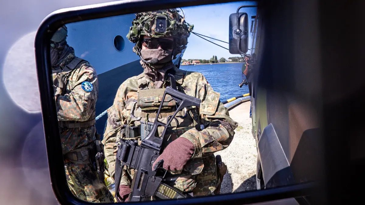 Bundeswehr-Übungsserie „Quadriga 2025“: 04.09.2025, Mecklenburg-Vorpommern, Rostock: Einheiten der Bundeswehr sichern bei einem Übungsszenario im Hafen das Beladen des 196 Meter langen Transportschiffs «Ark Germania» mit Militärtechnik ab. Im Rahmen des Militär-Manövers «Quadriga 2025» werden über 1.000 Militärfahrzeuge auf dem Seeweg nach Litauen transportiert. In diesem Jahr steht die Dimension See mit der Sicherung und dem Schutz von strategischen Seewegen und Infrastrukturen im Mittelpunkt der Übungsserie «Quadriga». Foto: Jens Büttner/dpa +++ dpa-Bildfunk +++