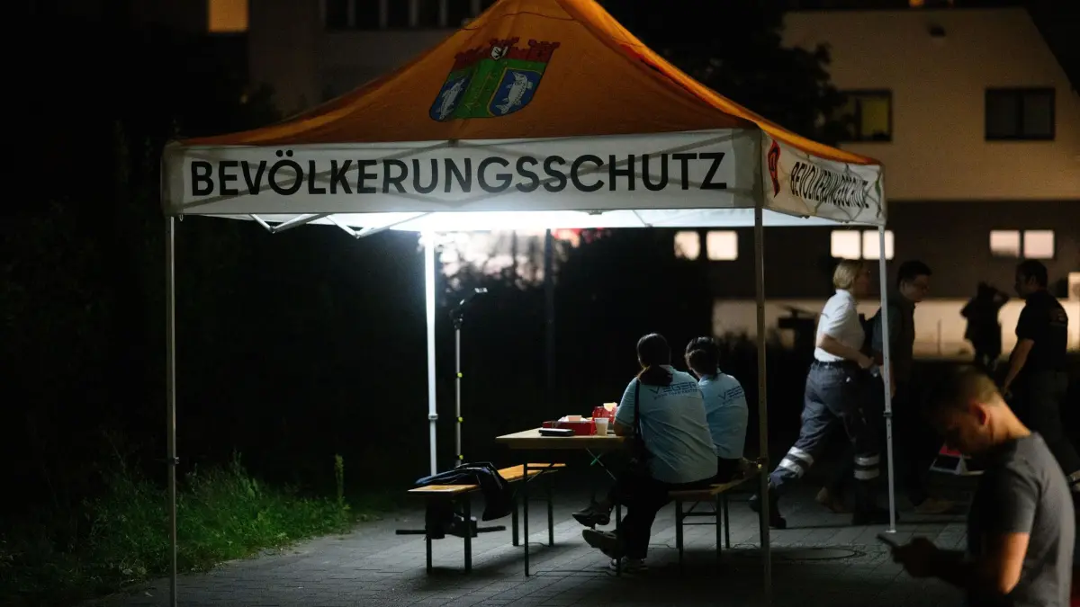 Stromausfall im Berliner Südosten: 09.09.2025, Berlin: Helfer sitzen vor einer Anlaufstelle des Deutschen Roten Kreuzes (DRK) für Anwohner in Adlershof. Betroffene können dort Hilfe bekommen oder ihre Handys aufladen. Wegen eines Brandanschlags auf zwei Strommasten kam es im Berliner Südosten zu einem großflächigen Stromausfall. Rund 43.000 Haushalte und 3.000 Firmen waren zunächst betroffen. Die Reparaturarbeiten dauern an. Foto: Bernd von Jutrczenka/dpa +++ dpa-Bildfunk +++