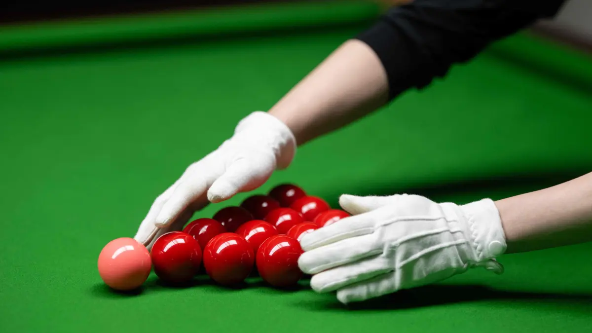 Cody Liu racks snooker balls for his son, the Hong Kong born snooker player Shaun Liu, aged 15, as he practices in the Ding Junhui Snooker Academy in the centre of Sheffield, northern England on September 10, 2025. Since 1977 the Snooker World Championship has been held every year in Sheffield's 980-seat Crucible Theatre, with an estimated 500 million spectators watching the televised broadcast across 150 countries. China's Zhao Xintong is the reigning World Snooker Champion, the first Asian player to win the title, whilst China's Bai Yulu is the reigning winner of the World Women's Snooker Championship. Snooker remains incredibly popular in China, with around 50 million people playing the game and approximately 300,000 snooker clubs, however many professional Chinese players are based in Sheffield, England as the widely-acknowledged home of the sport. (Photo by Oli SCARFF / AFP)