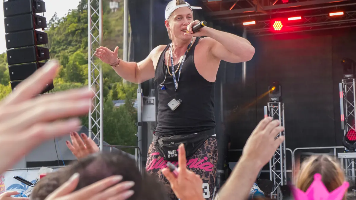 Tübingen, Mallorca Sommer Festival Tübingen 2025. Calvin Kleinen, der Bierkönig von Mallorca, singt: Wahnsinn, warum schickst du mich in die Hölle und aus beinahe tausend Kehlen erklingt der Refrain Hölle, Hölle, Hölle.