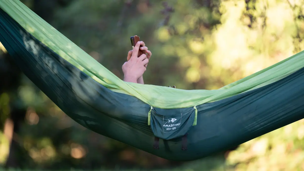 Spätsommer in Sachsen: 19.09.2025, Sachsen, Dresden: Ein Passant liegt in einer Hängematte und hält ein Smartphone. Foto: Sebastian Kahnert/dpa +++ dpa-Bildfunk +++