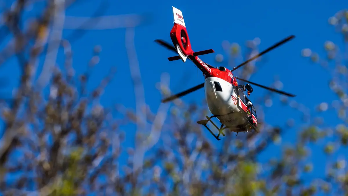ARCHIV - 23.04.2021, Baden-Württemberg, Ihringen: Ein Helikopter der DRF Luftrettung schwebt am Himmel über einem Waldstück. (zu dpa: «Kletterer stürzt in der Sächsischen Schweiz ab und stirbt») Foto: Philipp von Ditfurth/dpa +++ dpa-Bildfunk +++