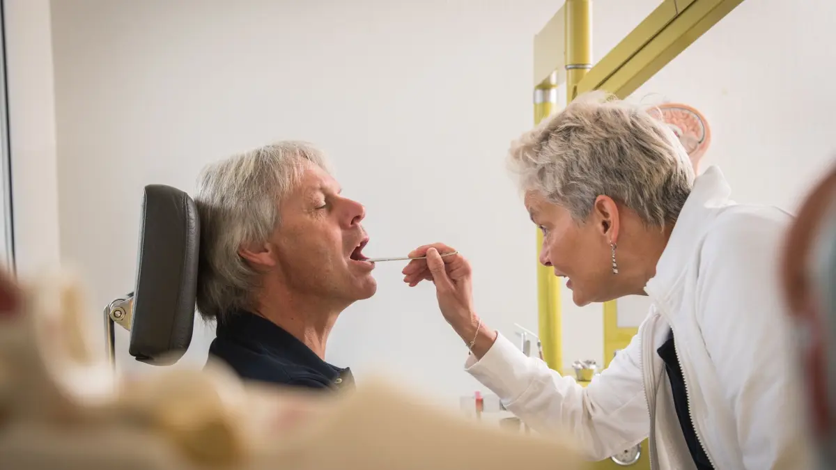 Ein Mann bei HNO-Ärztin: ILLUSTRATION - Was fehlt ihnen denn? Arbeitgeber haben zwar grundsätzlich keinen Anspruch auf Mitteilung von Diagnosen oder Symptomen, dürfen aber ohne Gründe die Vorlage eines ärztlichen Attests verlangen. (zu dpa: «Krankmeldung: Was ist erlaubt und was nicht?») Foto: Christin Klose/dpa-tmn - Honorarfrei nur für Bezieher des dpa-Themendienstes +++ dpa-Themendienst +++