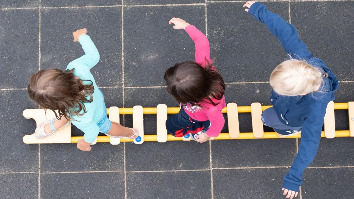 ARCHIV - 20.08.2021, Sachsen, Dresden: Kinder balancieren während eines Pressetermins auf dem Spielplatz einer Kita auf einem Brett. (zu dpa: «Kommission für Teilhabe von Kindern startet») Foto: Sebastian Kahnert/dpa-Zentralbild/dpa +++ dpa-Bildfunk +++