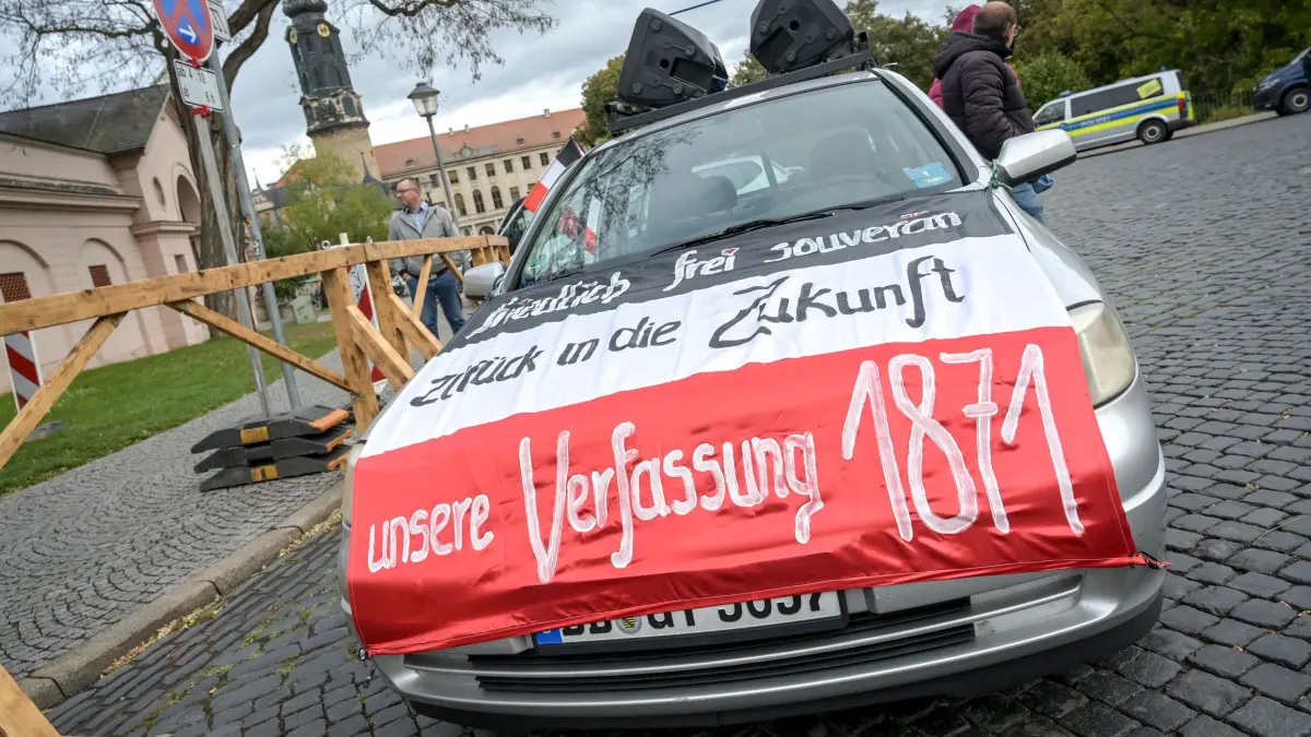 Bundesweites Treffen der Reichsbürgerszene in Weimar: 04.10.2025, Thüringen, Weimar: Ein Auto mit einem Transparent «Endlich frei und souverän – zurück in die Zukunft – unsere Verfassung 1871» bei einem bundesweiten Treffen von Anhängern der Reichsbürgerszene auf dem Platz der Demokratie. Danach ziehen die Teilnehmer durch die Innenstadt. Foto: Heiko Rebsch/dpa +++ dpa-Bildfunk +++