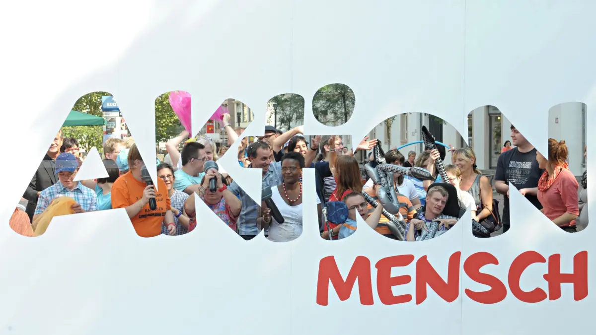 Im Rahmen der "Aktion Mensch"-Städtetour tanzen am Mittwoch (05.09.2012) in Stuttgart Menschen auf dem Kronprinzenplatz, zu sehen durch ein Transparent. Die Aktion Mensch ist eine durch Lotterie- und Spendeneinnahmen finanzierte Sozialorganistation, die mit der Städtetour das Thema Inklusion von Behinderten vermitteln will. Inklusion soll separierende Einrichtungen für Menschen mit Behinderung überflüssig machen und Ihnen Gleichstellung und Teilhabe in allen Belagen garantieren. Foto: Franziska Kraufmann dpa/lsw +++(c) dpa - Bildfunk+++
