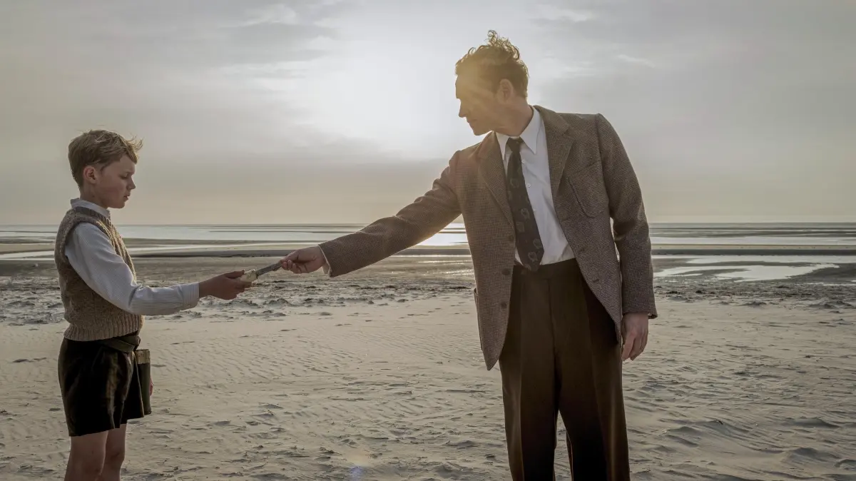 Der Film „Amrum“ kommt in die Kinos: Szenenfoto mit Nanning (Jasper Billerbeck, l.), Onkel Theo (Matthias Schweighoefer (Schweighöfer)) in Fatih Akins Film "Amrum", der am Donnerstag (09.10.2025) in die Kinos kommt. Fatih Akin bringt mit "Amrum" die Kindheitserinnerungen seines Freundes Hark Bohm, selbst Regisseur und Drehbuchautor, auf die Leinwand. Ein zwoelfjaehriger Junge, hier heisst er Nanning, ist mit seiner Familie vor dem Krieg auf die Insel gefluechtet. Der Vater ist in Gefangenschaft geraten, die Mutter hochschwanger – beide Eltern sind stramme Nazis, die Mutter faellt nach Hitlers Tod in eine tiefe Depression. Nanning liebt sie trotzdem und moechte ihr einen dringenden Wunsch erfuellen: Weissbrot mit Butter und Honig. Indem er nach Nahrungsmitteln fahndet, erkundet Nanning die Insel mit ihren Bewohnern. (Siehe epd-Filmkritik vom 07.10.2025) -- ACHTUNG: VEROEFFENTLICHUNG DES FOTOS NUR IM ZUSAMMENHANG MIT BERICHTERSTATTUNG UEBER DEN FILM SECHS WOCHEN NACH START DES FILMS GESTATTET!