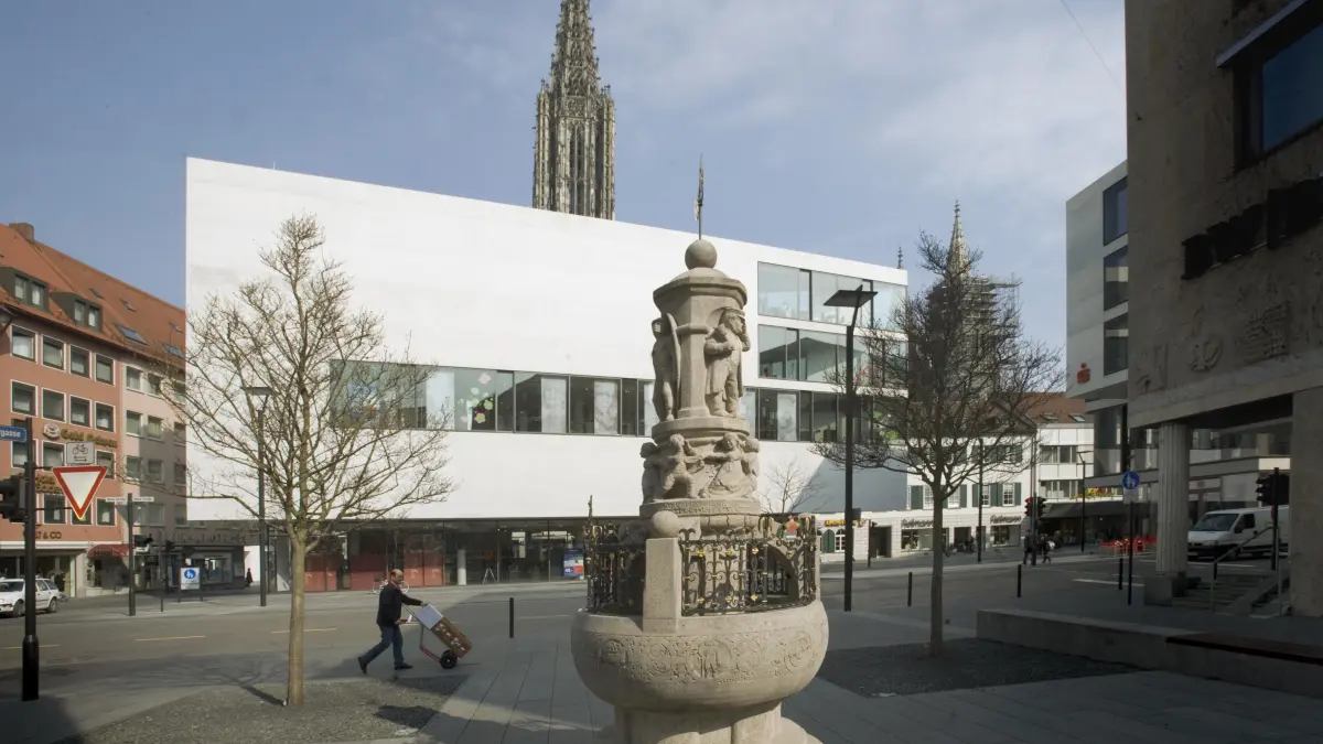 Ulm, Neue Straße, „Neue Mitte“, Kaufhaus „Münstertor“: Blick von der Sattlergasse über den historischen Brunnen auf das Kaufhaus "Münstertor" mit dem "Haus der Sinne" (Gebr. Salzmann), dahinter ragt der Turm des Ulmer Münsters empor
