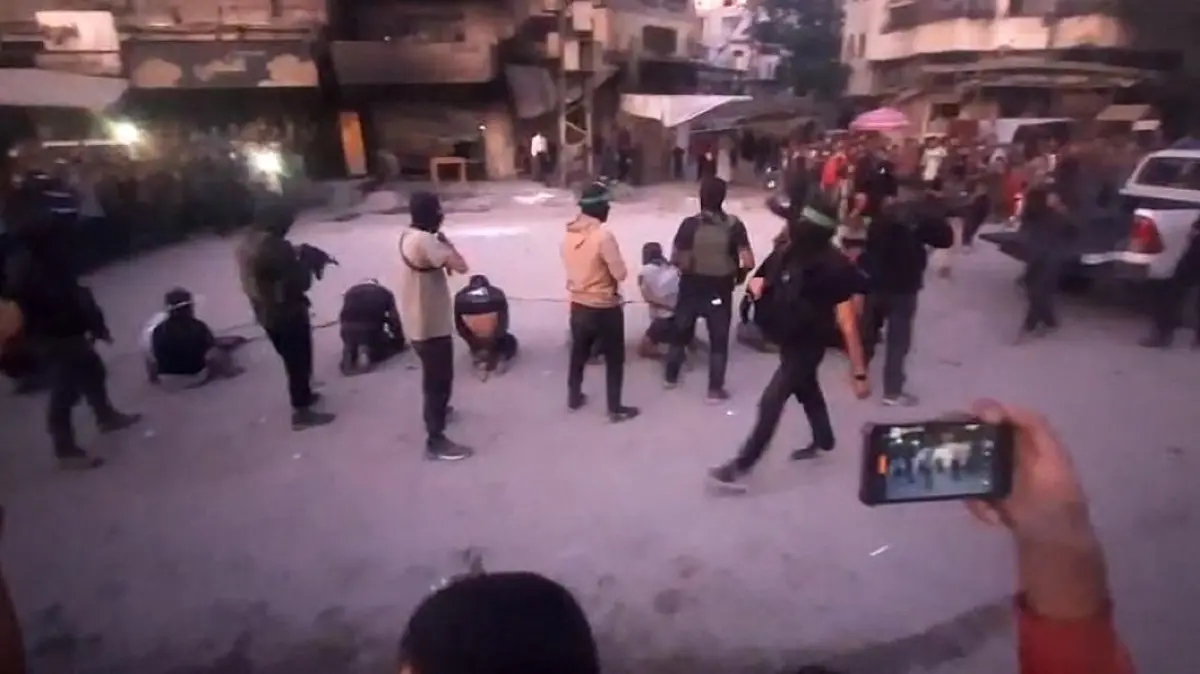This image grab from a handout video released by the Hamas-run al-Aqsa TV's Telegram channel on October 13, 2025, shows armed Hamas fighters standing behind blindfolded, bound and kneeling men as a crowd surrounds them in a street in Gaza City. The Hamas militant group has published an online video showing its fighters executing eight blindfolded, bound and kneeling men in the street. Hamas's armed groups are carrying out a campaign against Palestinian criminal gangs and clans in Gaza in the wake of a ceasefire with Israeli forces. (Photo by Al-Aqsa TV / AFP) / RESTRICTED TO EDITORIAL USE - MANDATORY CREDIT "AFP PHOTO / AL-AQSA TV "- HANDOUT - NO MARKETING NO ADVERTISING CAMPAIGNS - DISTRIBUTED AS A SERVICE TO CLIENTS