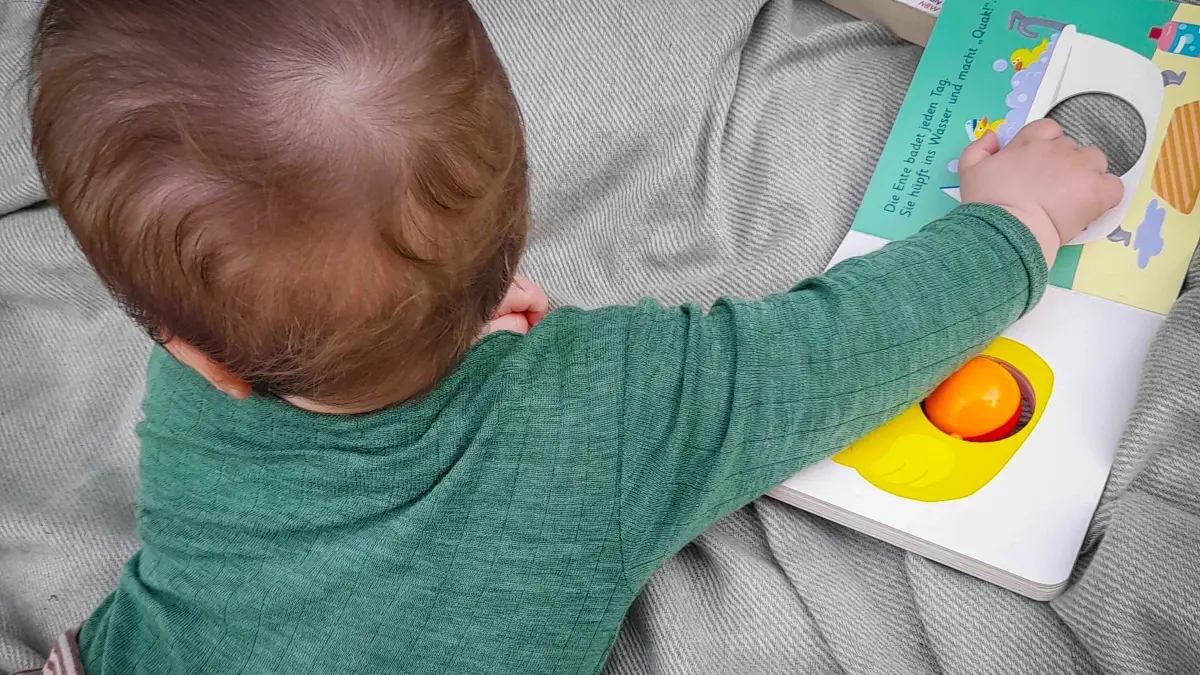 Ein sieben Monate altes Baby spielt auf einer Decke