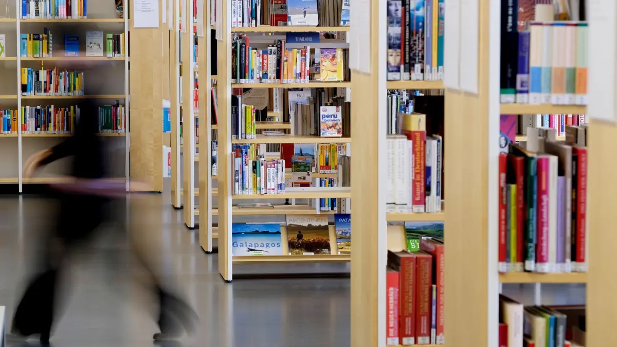 Stadtbibliothek: ARCHIV - 21.10.2016, Sachsen, Leipzig: Eine Mitarbeiterin der Stadtbibliothek geht an Bücherregalen vorbei. Die städtische Bücherei in Siegburg ist als Bibliothek des Jahres 2025 in der Kategorie kleinere Kommunen und Regionen ausgezeichnet worden. (zu dpa: «Erstes 24/7-Angebot am «Tag der Bibliotheken»») Foto: Sebastian Willnow/dpa-Zentralbild/dpa +++ dpa-Bildfunk +++