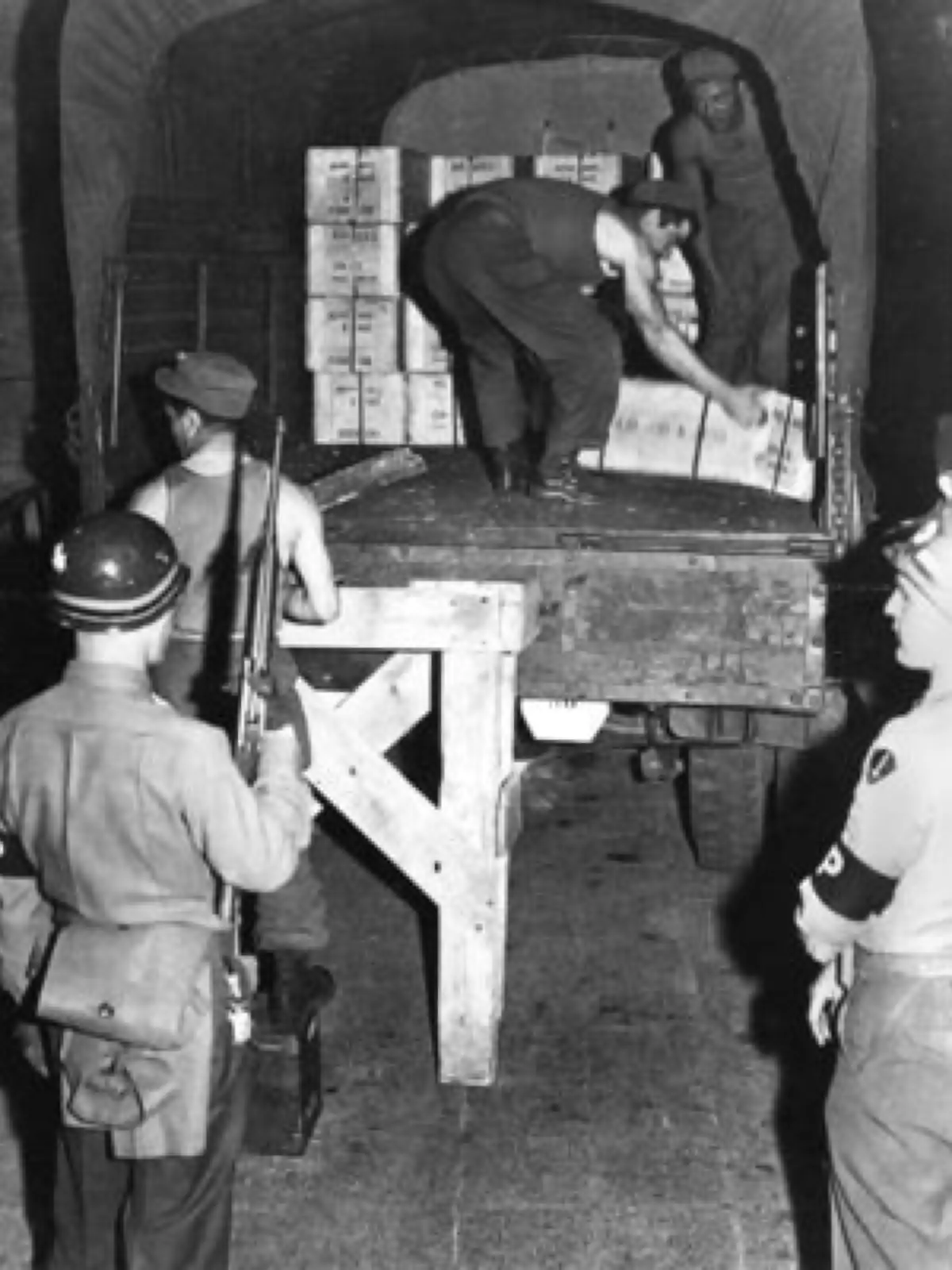 Juni 1948, wenige Stunden vor der Währungsreform: In Frankfurt werden Kisten mit dem neuen deutschen Geld unter starker Bewachung der Militärpolizei auf Lkw verladen und über die drei Westzonen verteilt. Das Geld wurde in Übersee gedrückt.
