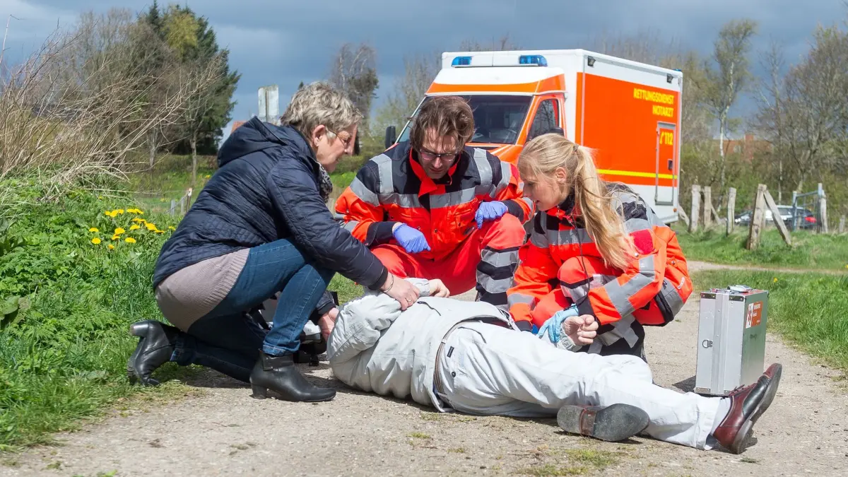 Rettungsdienst untersucht bewustlosen Mann: ILLUSTRATION - Können Sie Erste Hilfe leisten? Dann kann es mitunter sinnvoll, das zunächst zu tun, ehe Sie den Notruf wählen. (zu dpa: «Straftat beobachtet? So verhalten sich Zeugen richtig») Foto: Benjamin Nolte/dpa-tmn - Honorarfrei nur für Bezieher des dpa-Themendienstes +++ dpa-Themendienst +++