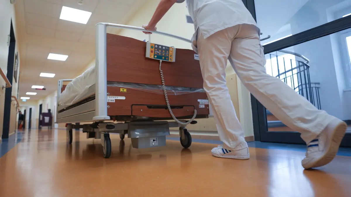 Krankenhaus: ARCHIV - 24.03.2025, Schleswig-Holstein, Bad Oldesloe: Eine Krankenschwester schiebt ein Bett über den Flur einer Krankenstation in der Asklepios Klinik Bad Oldesloe. (zu dpa: «Wie sich die Löhne in der Pflege entwickelt haben») Foto: Marcus Brandt/dpa +++ dpa-Bildfunk +++